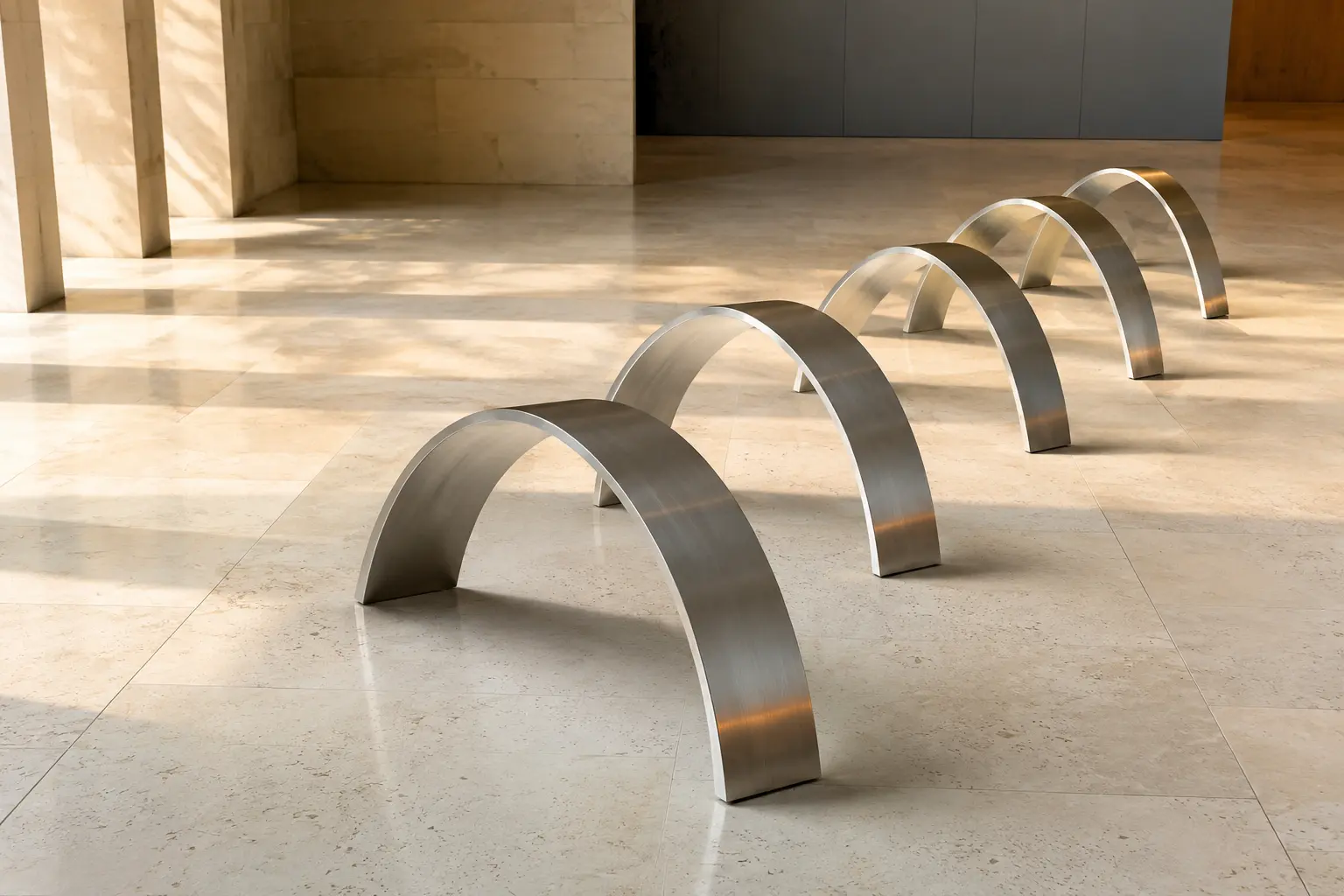 Five brushed metal arcs creating a measured sequence across a limestone floor